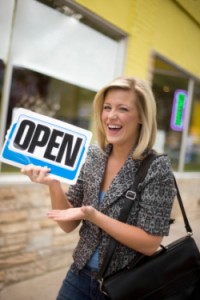 A happy owner holding up an Open sign in front of her new business